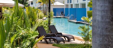 A pool area with lounge chairs and a pool.