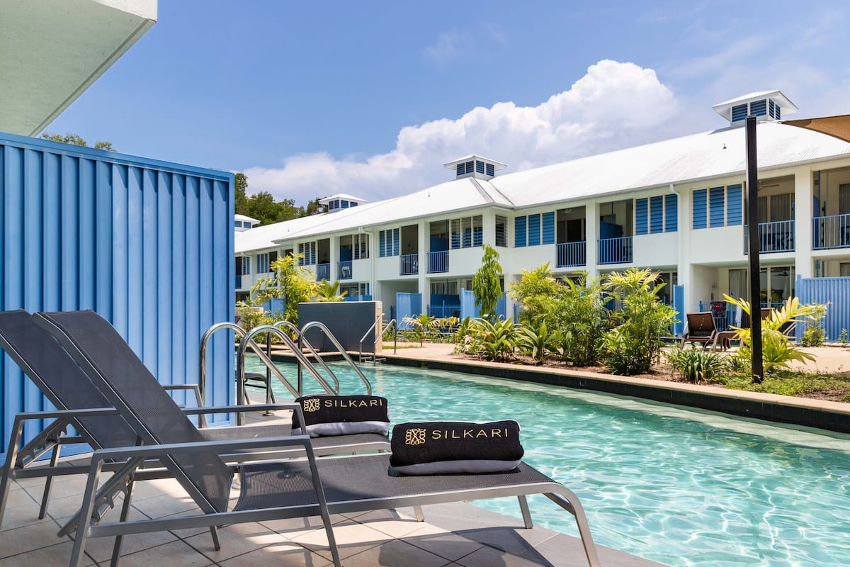 A pool area with lounge chairs and a building with balconies.