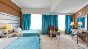 Quarto de hotel com duas camas, uma escrivaninha, uma cadeira, uma mesinha de cabeceira com abajur e um espelho.