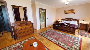 Een hotelkamer met een houten dressoir, een bed met hoofdeinde, een nachtkastje, een bureau met afstandsbediening en een groot vloerkleed.