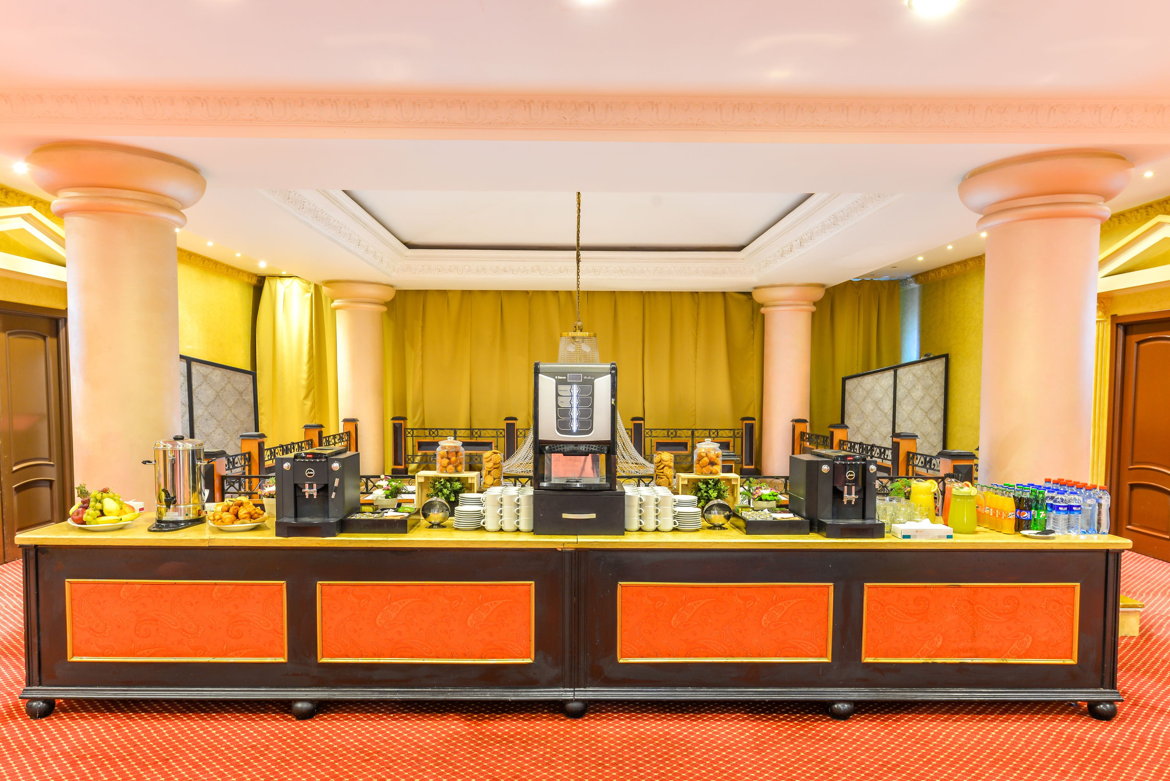 A hotel reception area with a counter, coffee machines, and a large mirror.