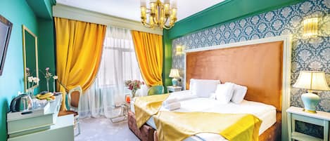 A hotel room with a large bed, a nightstand, a dresser, and a chandelier.