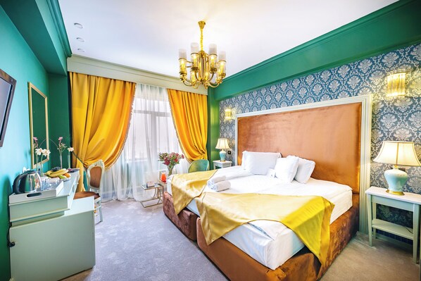 A hotel room with a large bed, a nightstand, a dresser, and a chandelier. - Phoenicia Grand Hotel (Bucharest)
