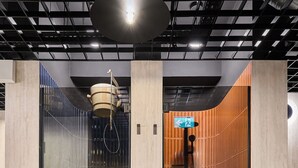 Un baño moderno con cabina de vidrio, pared de paneles de madera y zona de ducha a la vista.