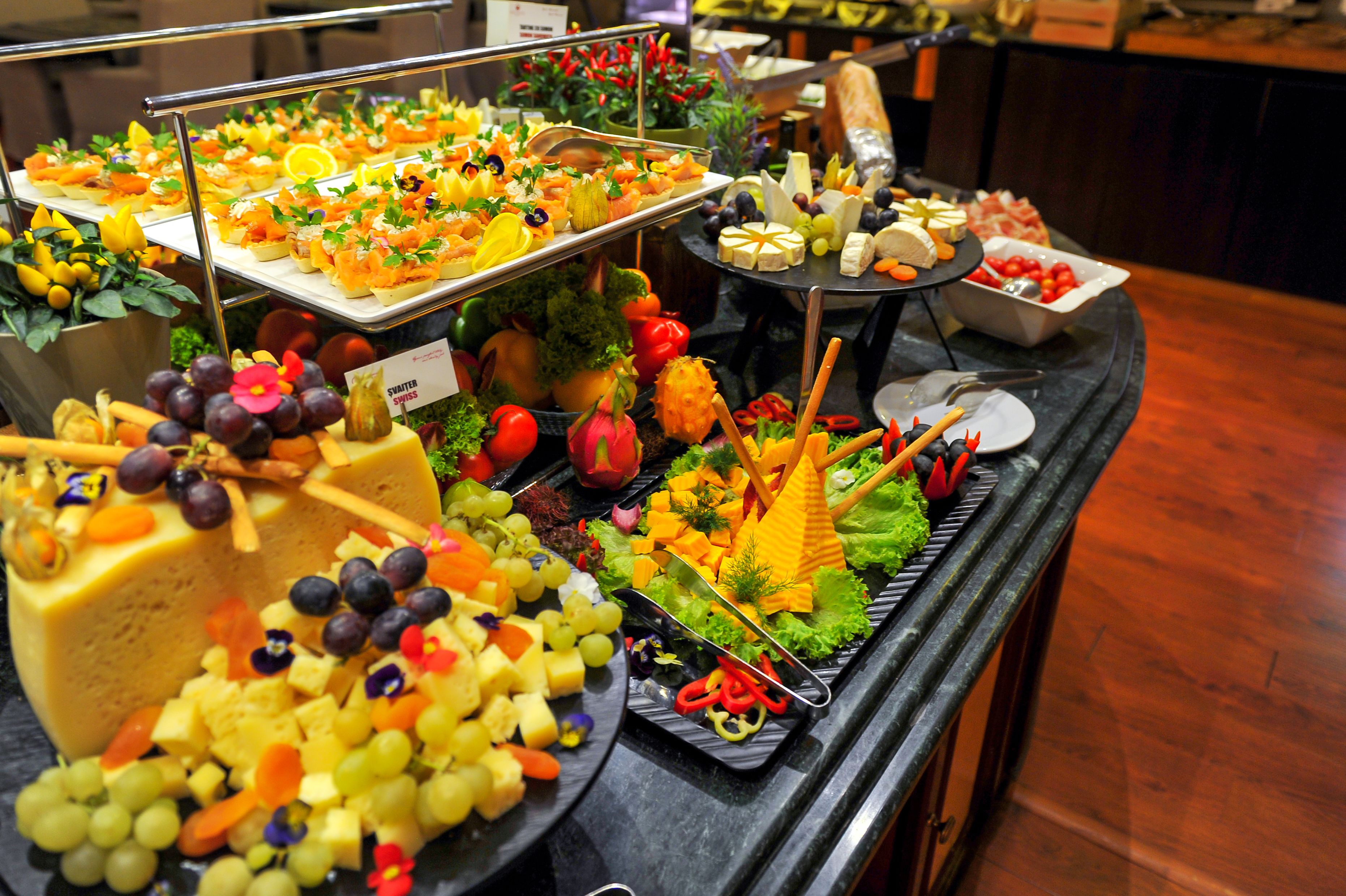 Un bufé con diversos quesos, frutas y verduras.