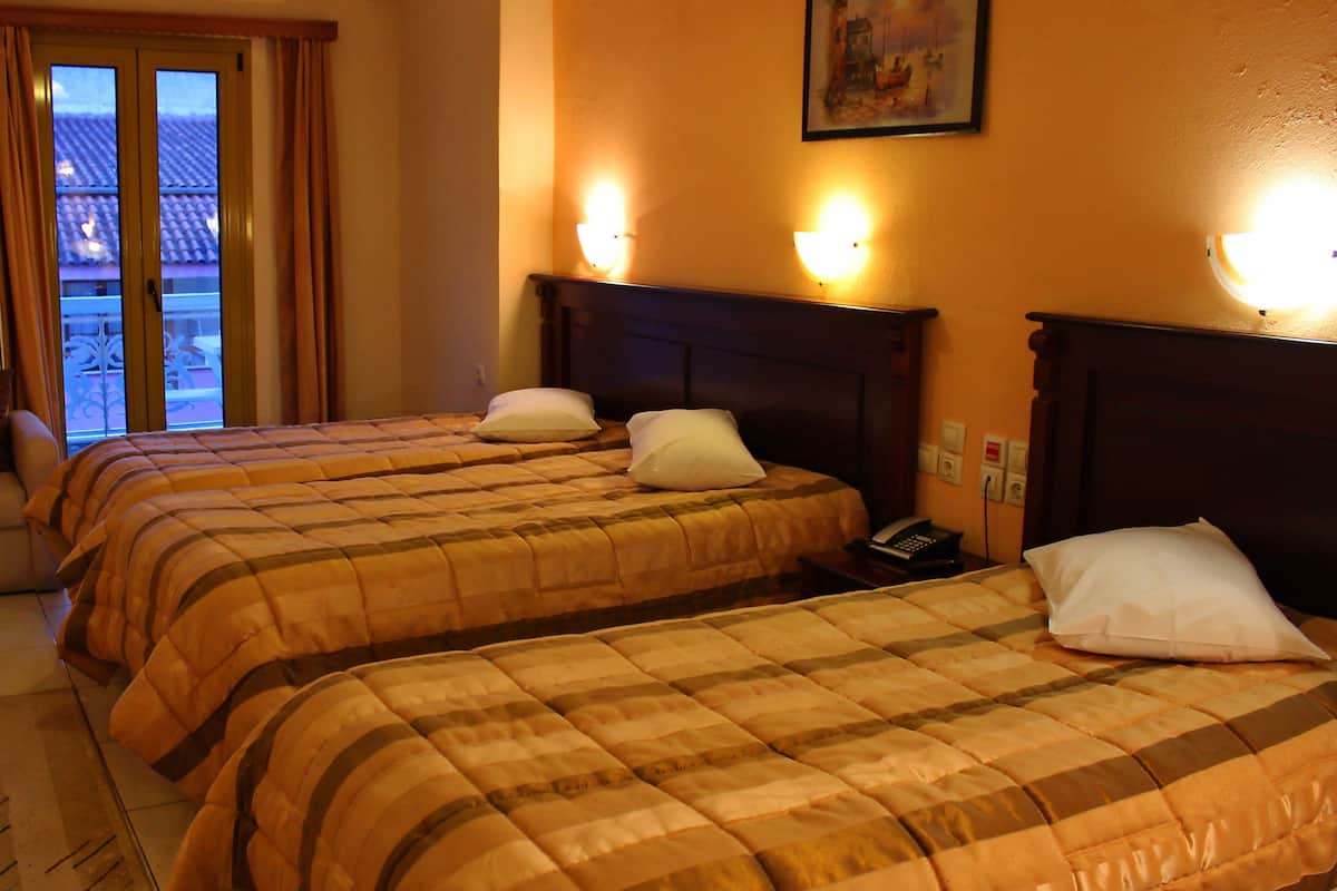 Een hotelkamer met twee bedden, een stoel, een raam met gordijnen en een schilderij aan de muur.