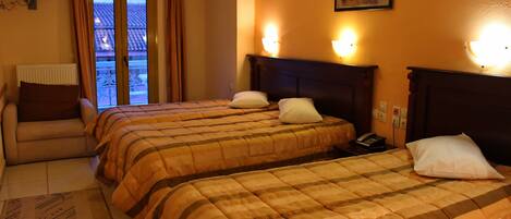 Habitación de hotel con dos camas, una silla, una ventana con cortinas y un cuadro en la pared.
