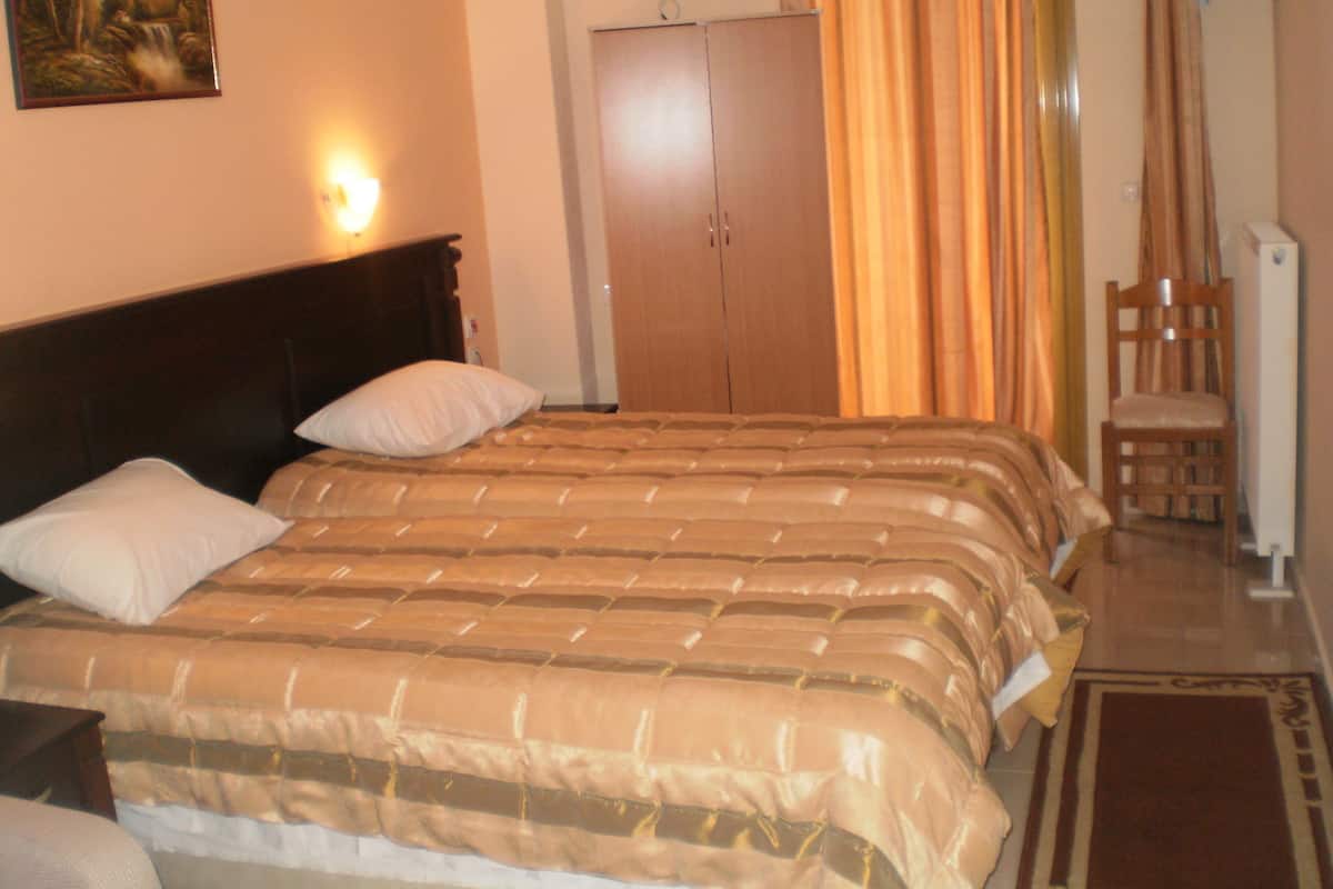 Een hotelkamer met een groot bed, een kledingkast, een stoel en een schilderij aan de muur.