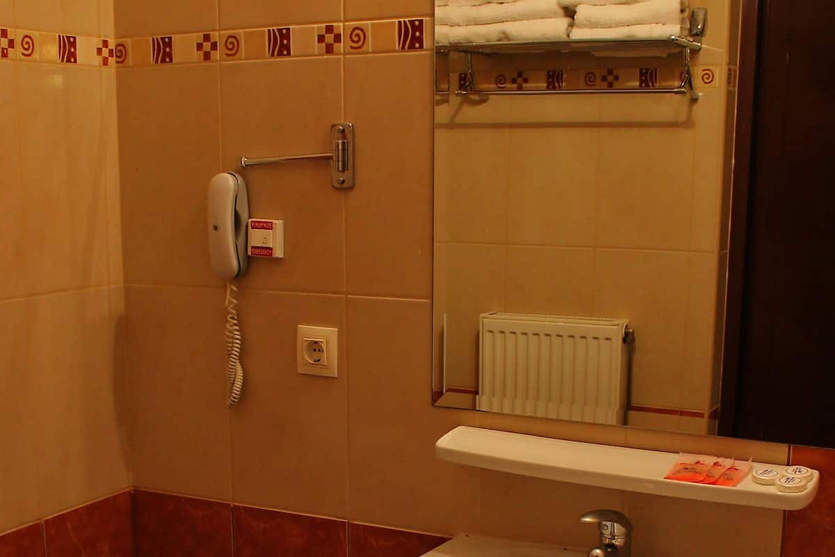Een badkamer met toilet, wastafel en een handdoekrek met handdoeken.