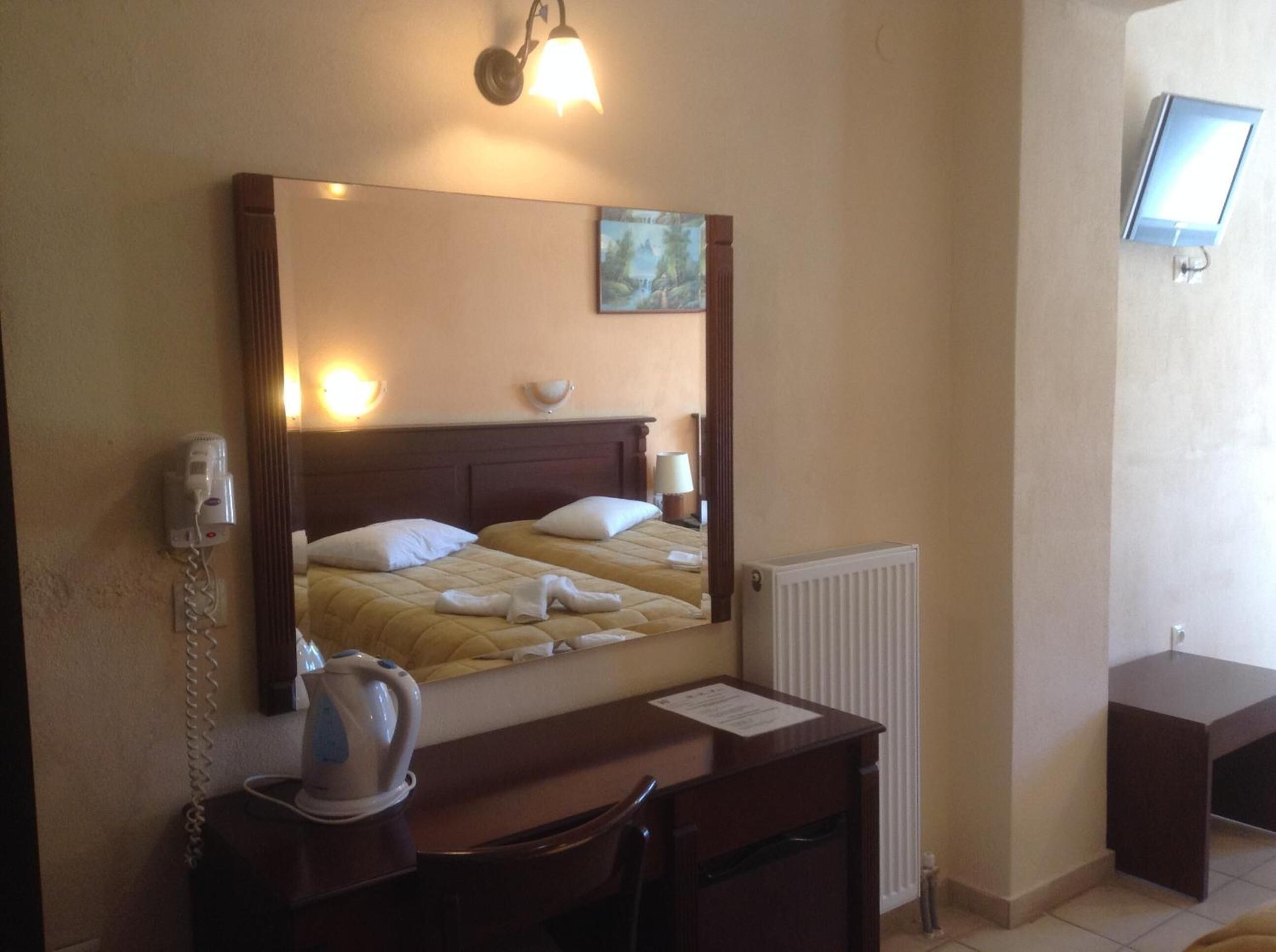 A hotel room with a bed, bedside table, and a desk.