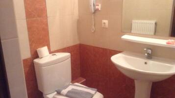 A small bathroom with a toilet, a sink, and a mirror.