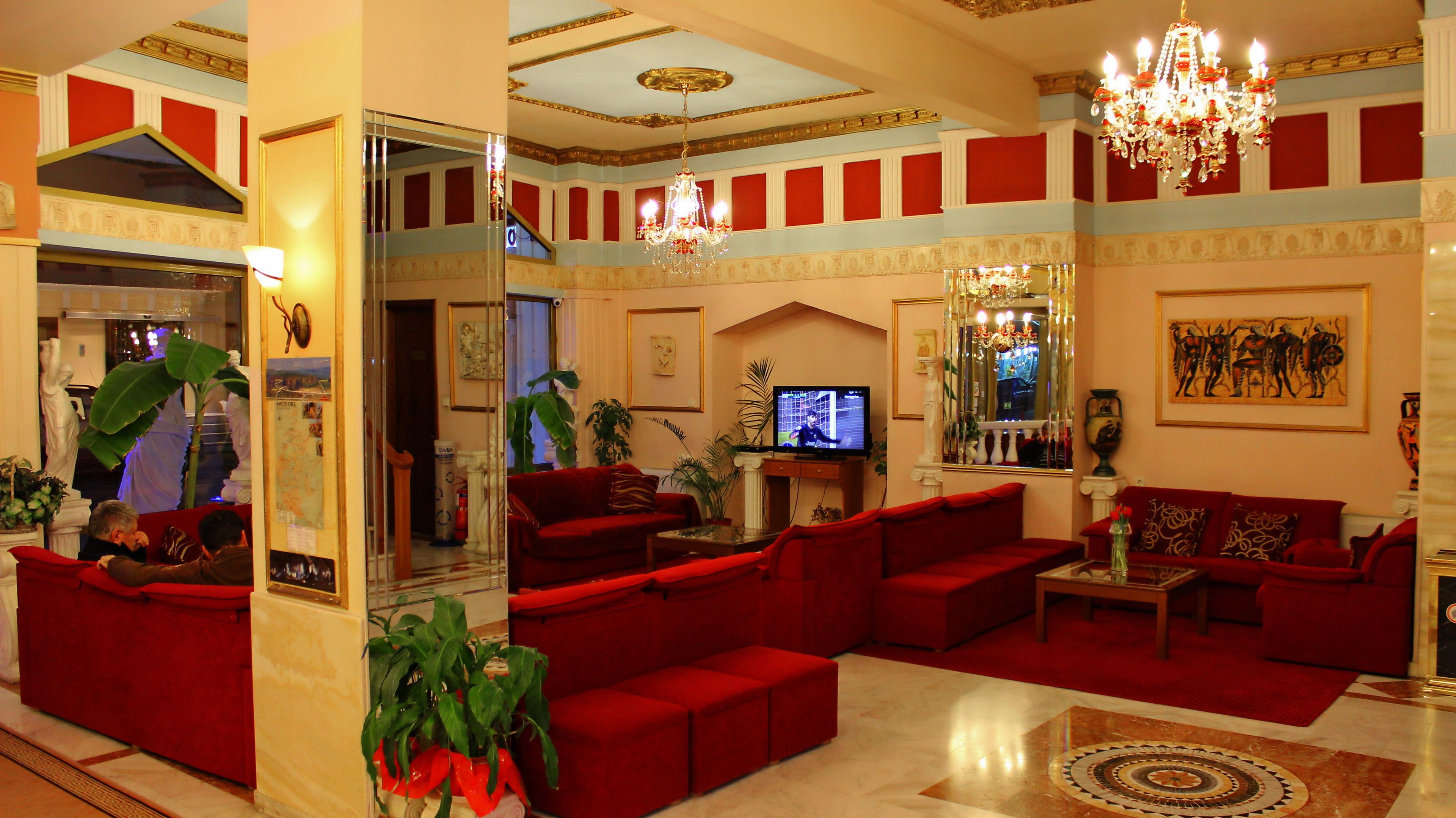 A spacious lobby with red sofas, a television, and a chandelier.