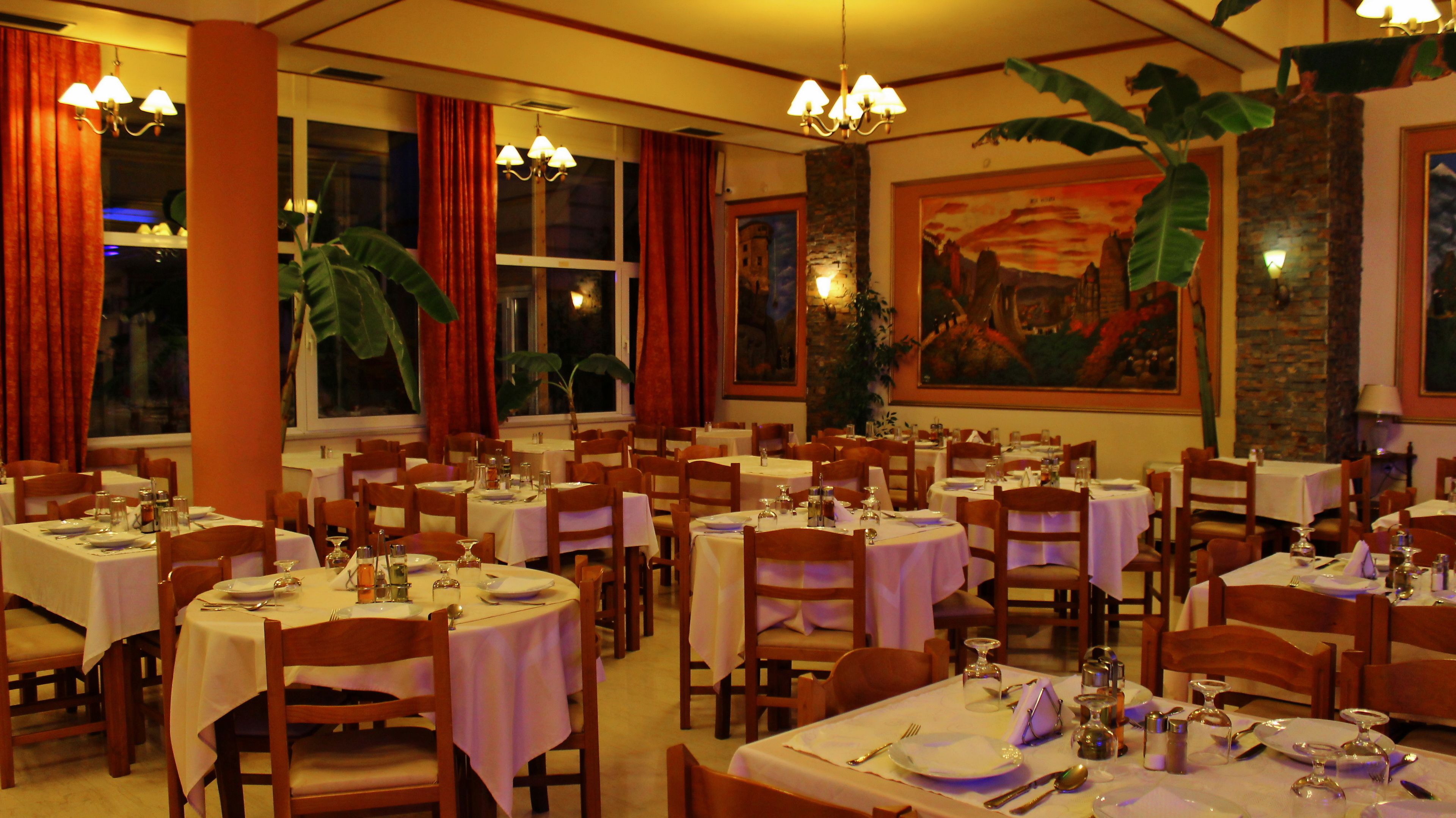 Un ristorante con tavoli rotondi, sedie in legno e lampadari.