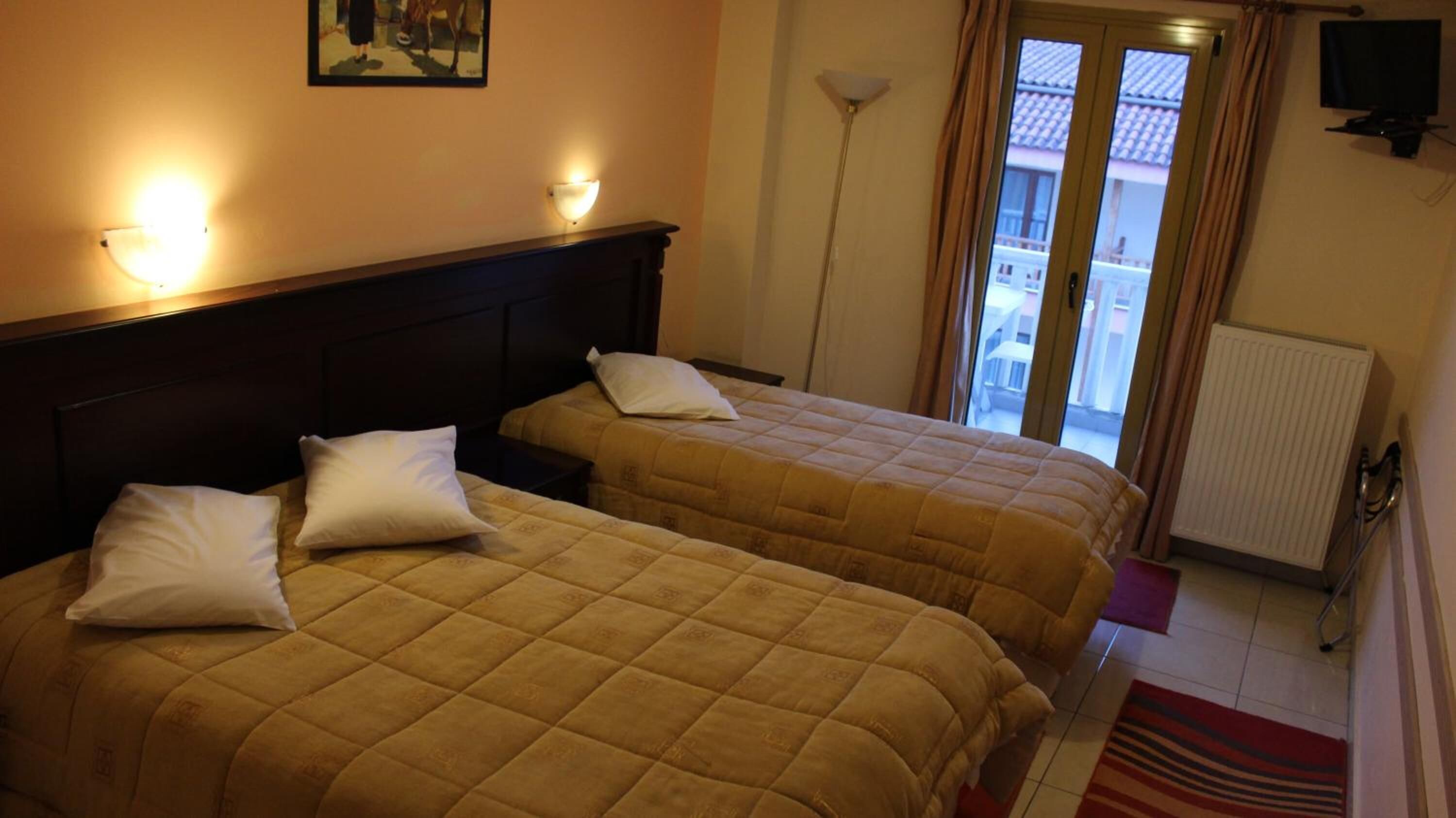 A hotel room with two beds, a painting on the wall, a TV, and a view of the outside balcony.