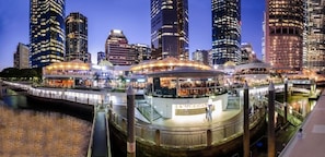 A waterfront hotel with a circular observation deck, a covered walkway, and a river.