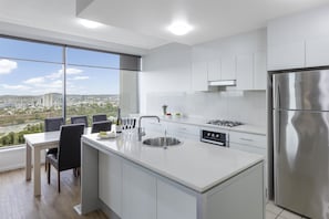 A modern kitchen with a large island, stainless steel appliances, and a view of a cityscape.