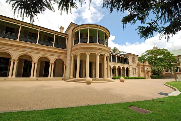 A large, classical building with a central courtyard, multiple balconies, and a curved structure with columns.