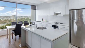 Een moderne keuken met een groot eiland, roestvrijstalen apparatuur en een uitzicht op een stadsgezicht.