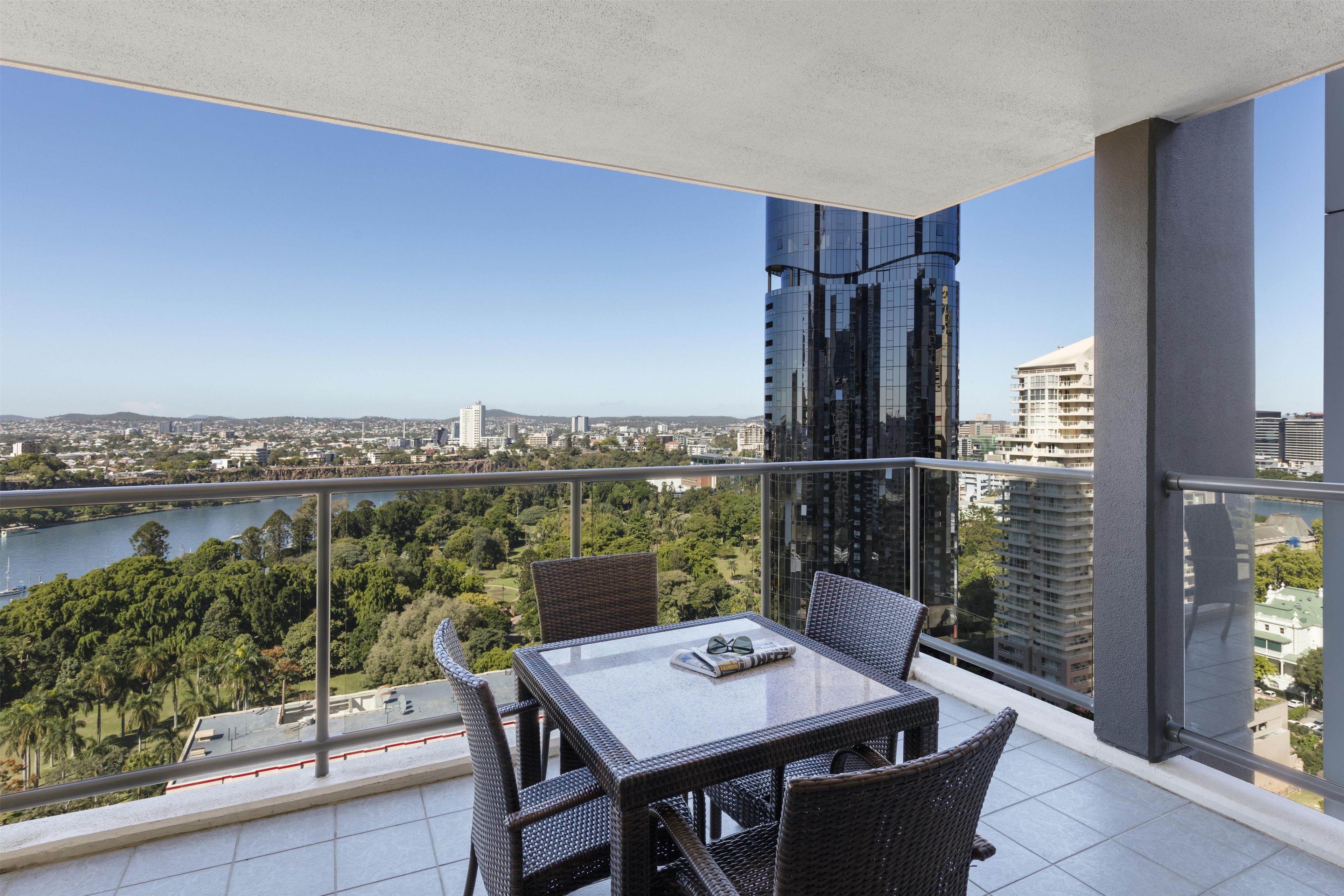 A balcony with a table and chairs, overlooking a cityscape and a body of water.