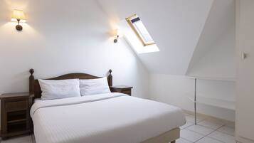 A bedroom with a large bed, two bedside tables, a nightstand, a window with a view, and a wall-mounted lamp.