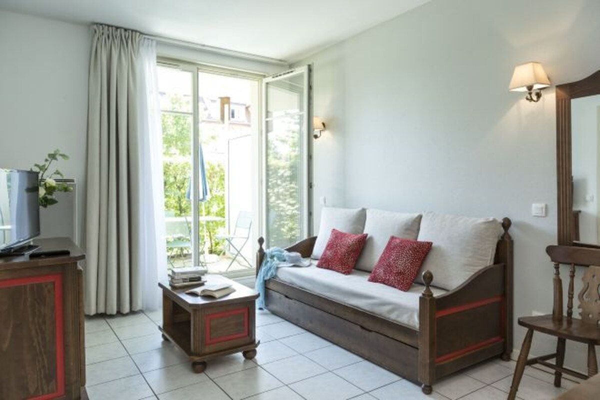 A cozy room with a bed, a small table, a TV, and a window with curtains.