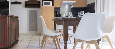 A modern kitchen with wooden cabinets, a microwave, and a dining table with white chairs.