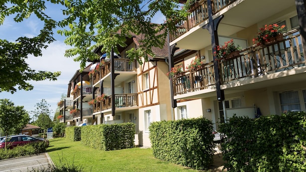 A multi-story hotel with balconies, a parking area, and well-maintained hedges. - Résidence Odalys Le Domaine des Rois (Bergheim)