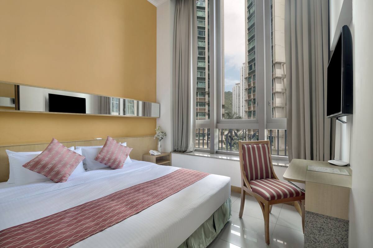 Une chambre d’hôtel avec un grand lit, un bureau, une chaise et un téléviseur.