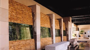 Un interior moderno con paredes de piedra, una fuente de agua reflectante y una zona de estar.