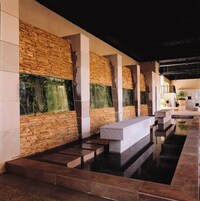 Un interior moderno con paredes de piedra, una fuente de agua reflectante y una zona de estar.