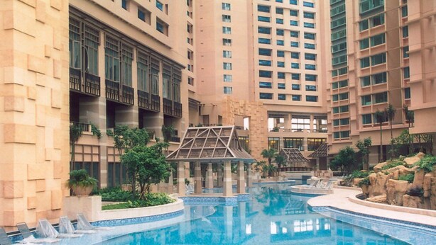 A large indoor swimming pool surrounded by high-rise buildings with balconies and a small pavilion. - Rambler Garden Hotel (Tsing Yi)