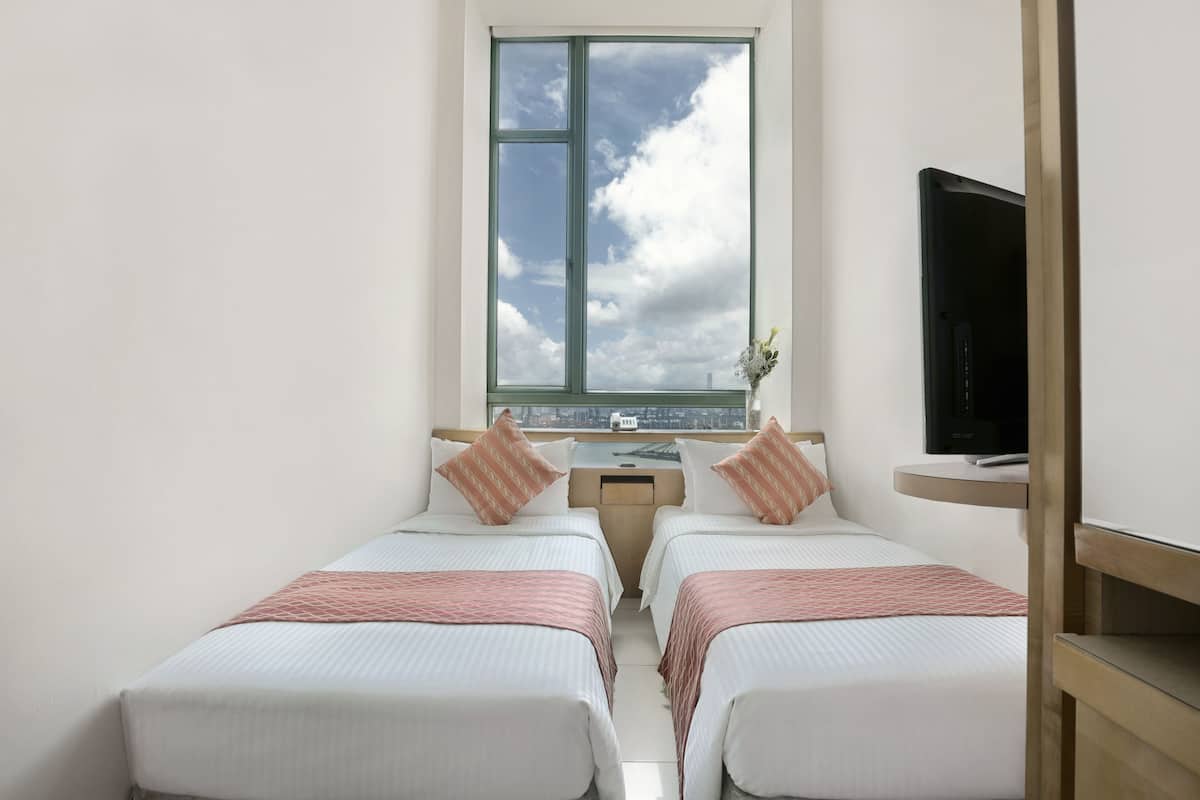Une chambre d’hôtel avec deux lits, un bureau, une télévision et une fenêtre donnant sur la ville.