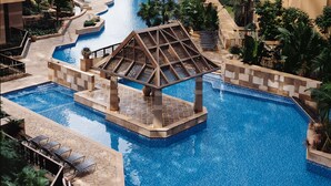 A large indoor swimming pool with a central pavilion, surrounded by high-rise buildings and lush greenery. - Rambler Garden Hotel (Tsing Yi)