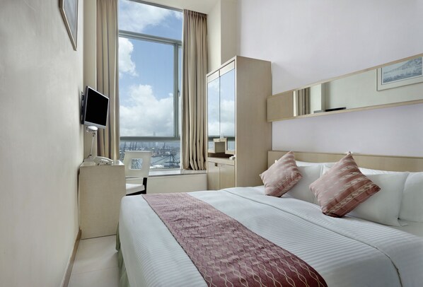 Une chambre d’hôtel avec un grand lit, une télévision, une armoire et une fenêtre donnant sur la ville.