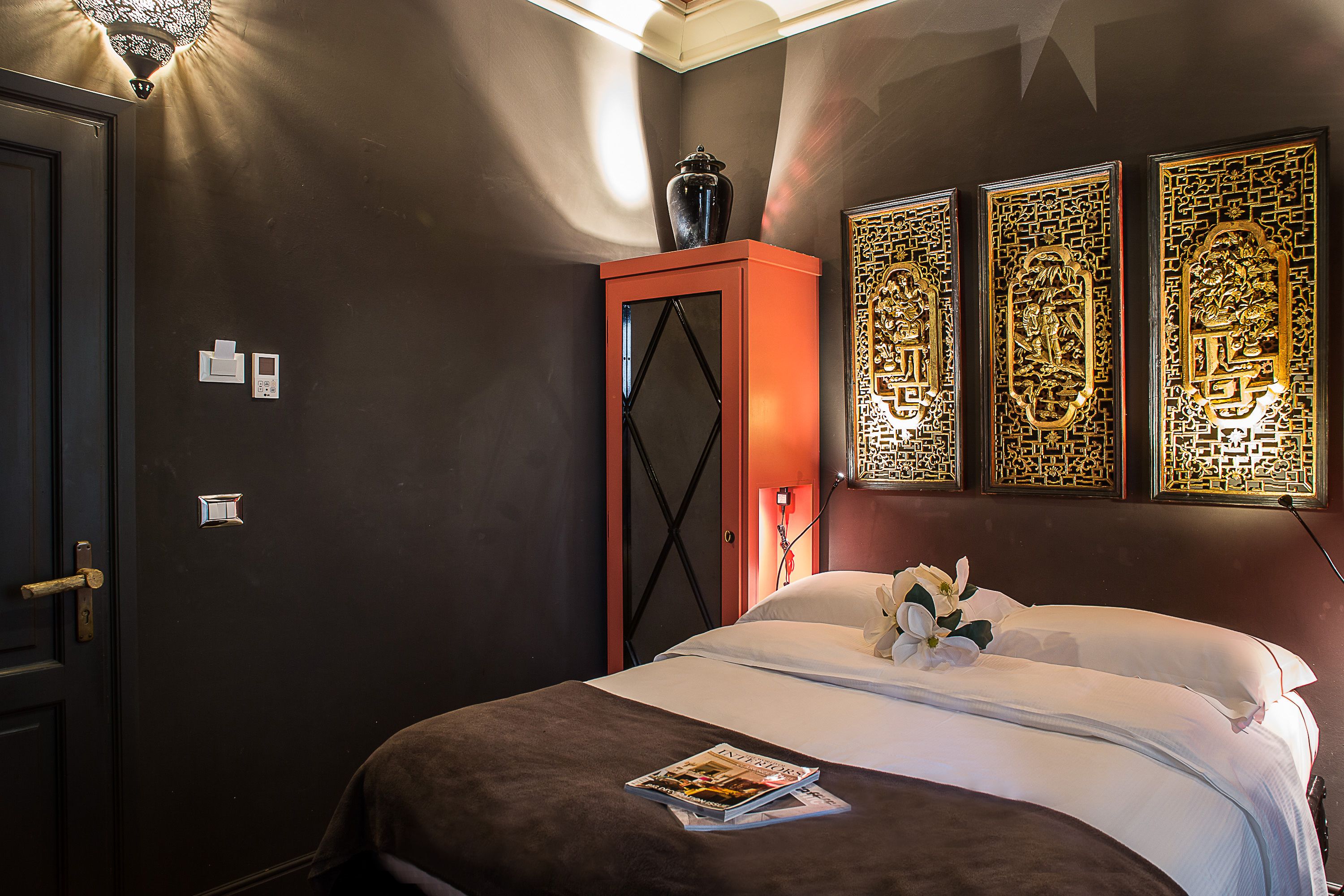 A hotel room with a bed, a cabinet, and decorative wall panels.