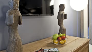 Un aparador de madera con una revista, un frutero y dos estatuas de piedra.