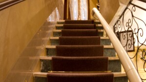 Eine imposante Treppe mit Marmorstufen und Metallgeländer, die zu einer höheren Etage führt.