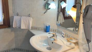 Ein Badezimmer mit Waschbecken, Spiegel, Handtuchhalter und einem Föhn.