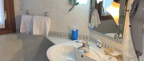 Un baño con lavamanos, espejo, toallero y secador de pelo.