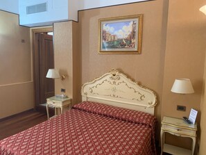 A hotel room with a bed, two bedside tables, a lamp, a painting, and a door. - Locanda Poste Vecie (Venice)