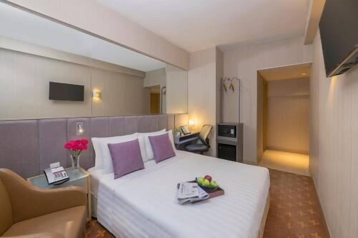 Une chambre d’hôtel comprenant un lit, un bureau avec une lampe, une chaise, une télévision et une salle de bain.