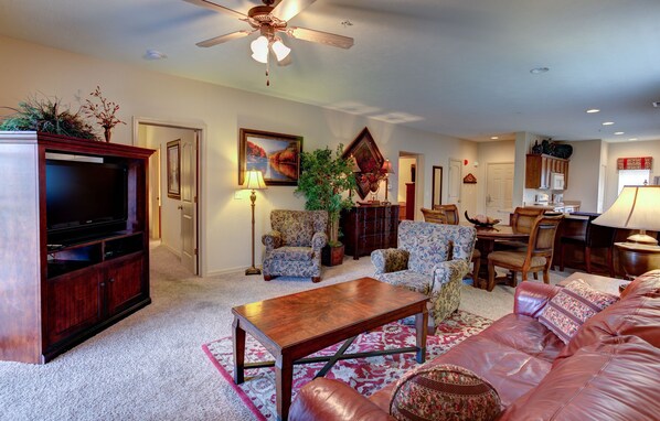 A living room with a television, sofa, coffee table, and dining area.