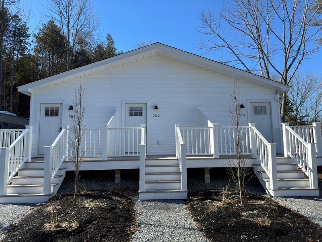 A white two-story building with numbered doors, a central staircase, and a small porch area.