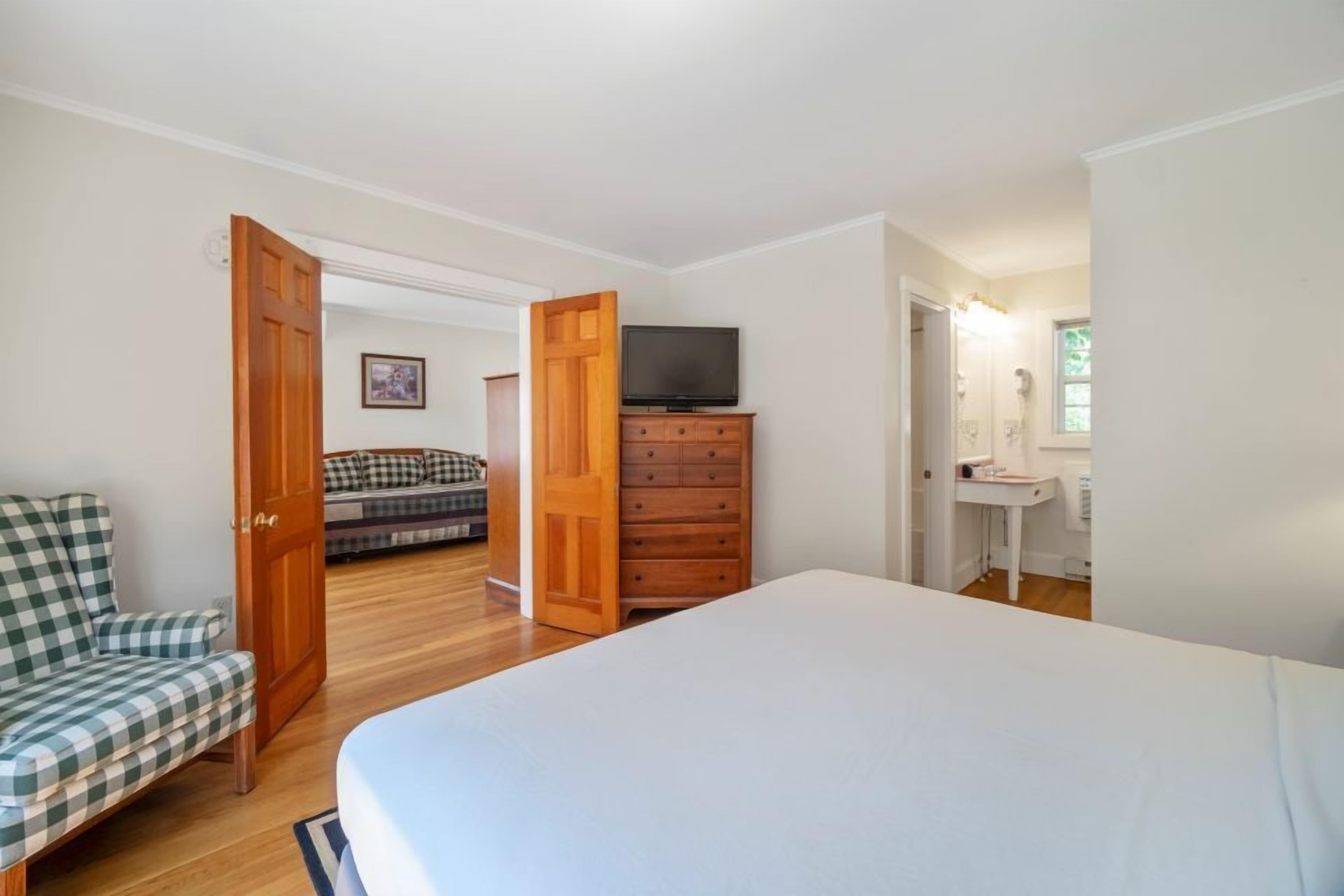 Un dormitorio con una cama, un aparador de madera, un televisor y una silla.