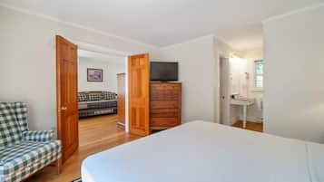 Un dormitorio con una cama, un aparador de madera, un televisor y una silla.