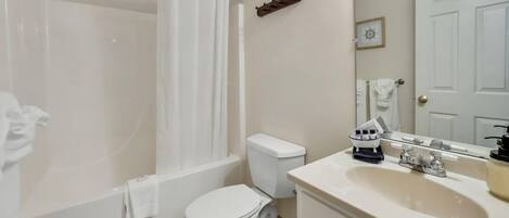 A bathroom with a bathtub, toilet, sink, and a mirror.