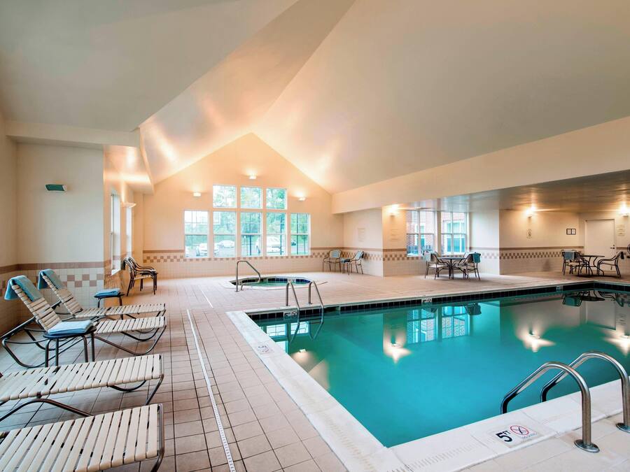 Una piscina interior con sillones de descanso y una habitación luminosa con ventanas.