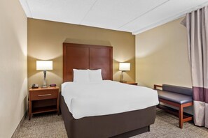 A hotel room with a bed, bedside tables, lamps, a chair, and a curtain. - Comfort Inn & Suites (Panama City)