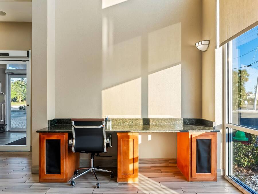 Um espaço de escritório moderno com escrivaninha, cadeira, janelas amplas e vista para o exterior.
