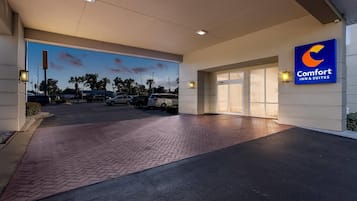 Indgang til Comfort Inn & Suites med en asfalteret indkørsel og en parkeringsplads i baggrunden.